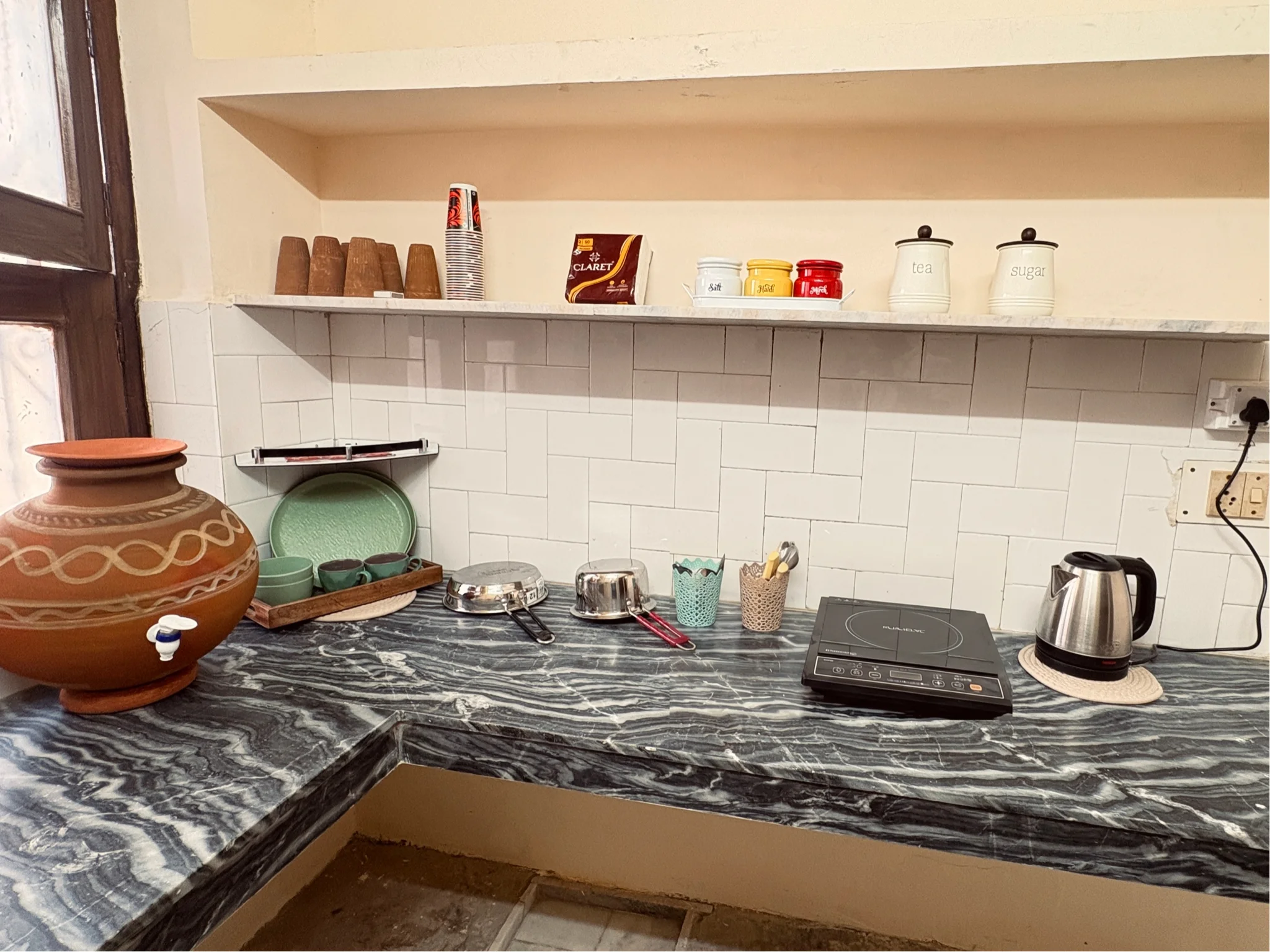 Kitchen counter with induction cooktop, kettle, and clay matka
