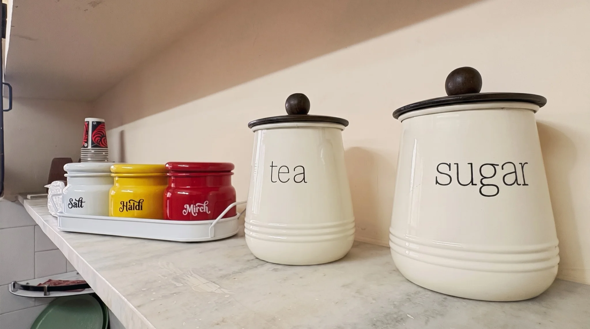 Tea, sugar, and masala jars on the kitchen shelf